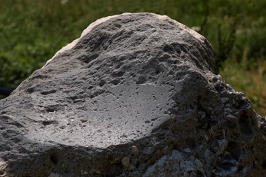 A close up photograph of the surface of a stone boulder showing it has been used for polishing.