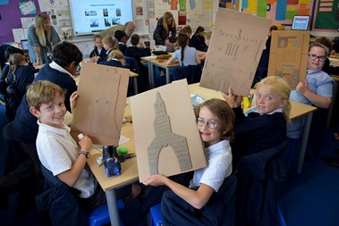 Children learning about a town’s history through recreating some of its buildings using recycled materials.