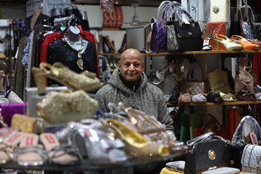 Portrait photo of a man surrounded by his shop displays of women's clothes, shoes and accessories.