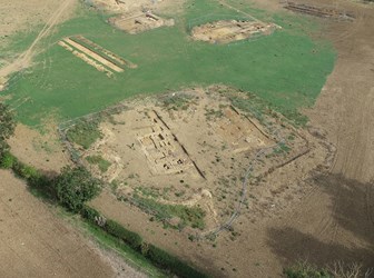 Aerial view of an excavation with trenches containing foundations of stone walls.