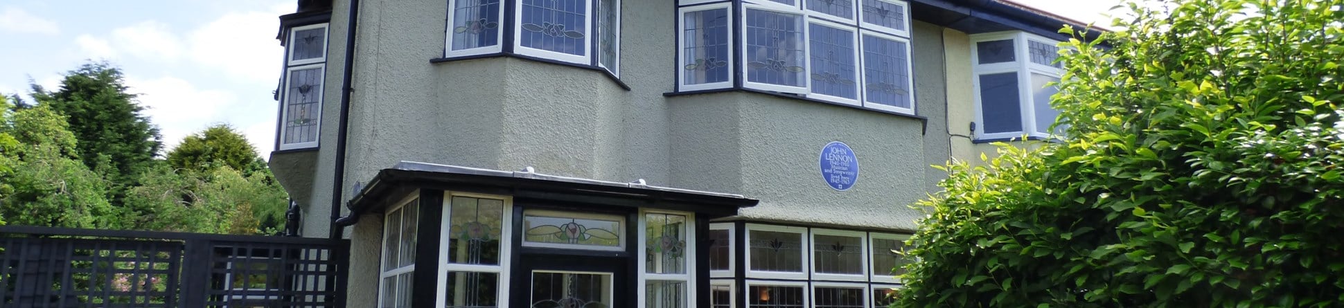 The front exterior of a semi-detached house in Liverpool with a Blue Plaque celebrating the singer, songwriter, musician and peace activist John Lennon