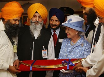 Queen Elizabeth II receives a ceremonial sword (tulwar) as a gift, at the end of a visit to the Sikh Gurdhwara Temple in Leicester. 1 August 2002 © PA Images / Alamy Stock Photo