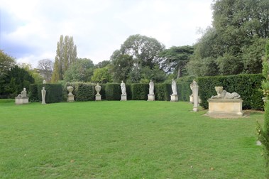 Stone statues situated along a hedge