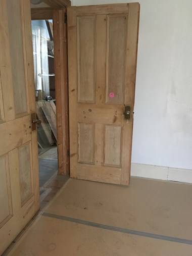 A double door with one leaf open, and a floor covered in cardboard sheets taped together.