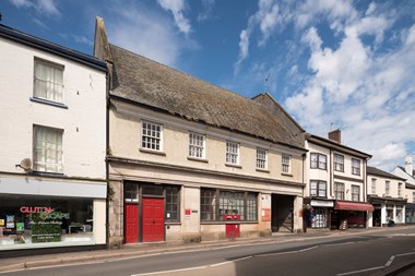 A view of a high street with a two-story stone building used as a Post Office