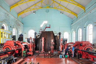Interior: volunteers working on the enormous double steam engine.  Also showing a cable winding drum (27.5 foot diameter)