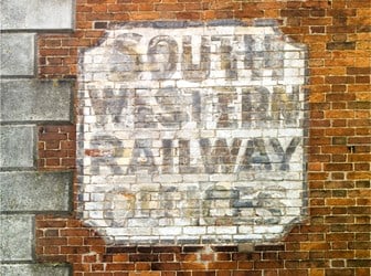 A close-up of a painted sign on a red brick wall.