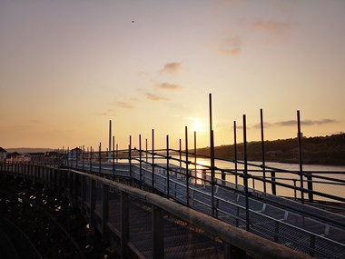 Dunston Staiths at sundown, as the sun sets just above the sea. The temporary scaffolding walkway is a silhouette in the foreground.