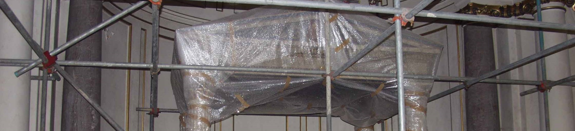 A baldaquin covered in bubble-wrap, flanked by two columns and surrounded by scaffolding.